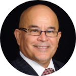 Photo of Fernando Gomez, Vice-President, a Latino bald man with rectangular glasses smiling