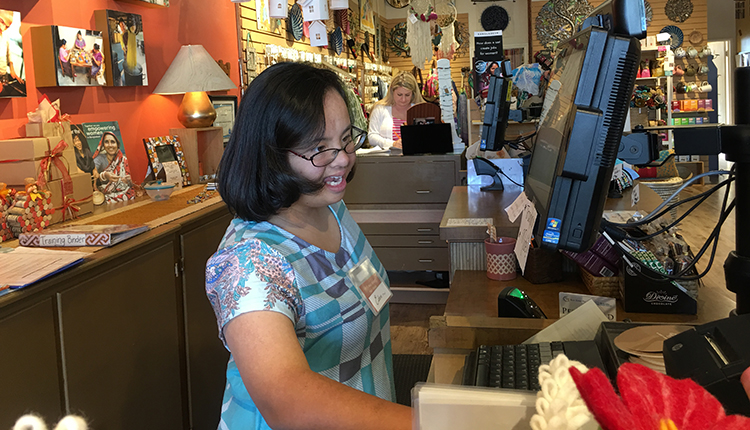 Eden Rapp, a young Asian woman with Down syndrome, working at a cash register in a gift store