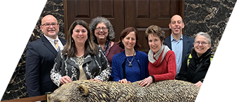 DVU board members and founders stand smiling with their hands on a statue of a bear in front of the Governor’s office in the California State Capitol.