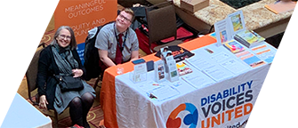 photo taken from above, two staff members smile up from a DVU booth at a conference